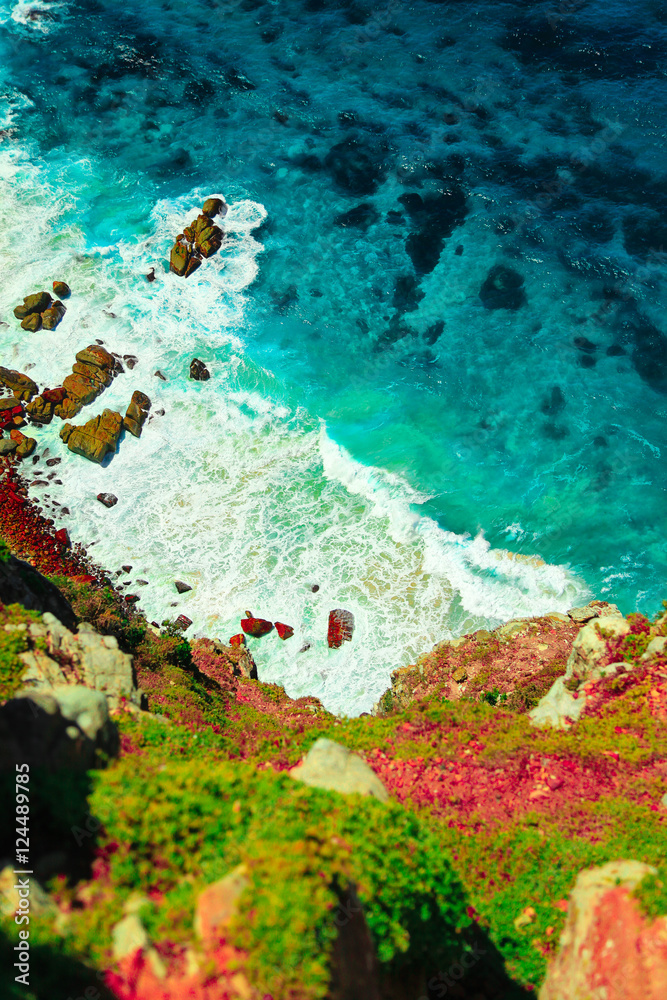 Sea turquoise water hitting rocks of steep cliff