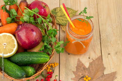 Морковный смузи в стеклянной банке с овощами на деревянном фоне. Здоровое питание.