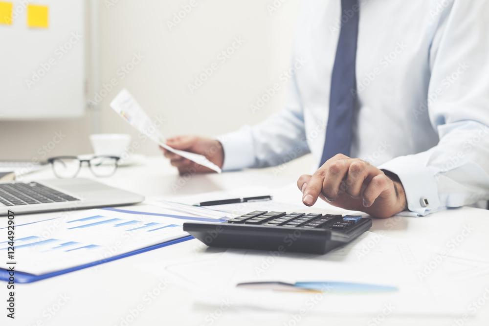 Man using calculator and holding document Man using calculator and holding document