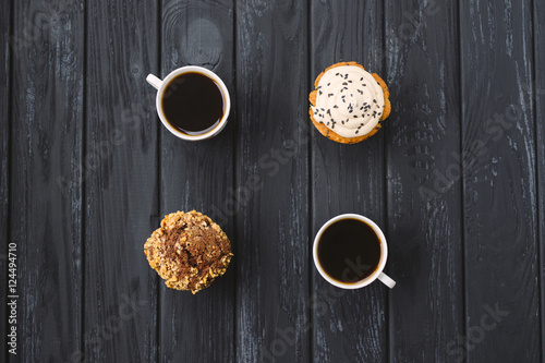 homemade muffins and two cups of cofee on black wooden background