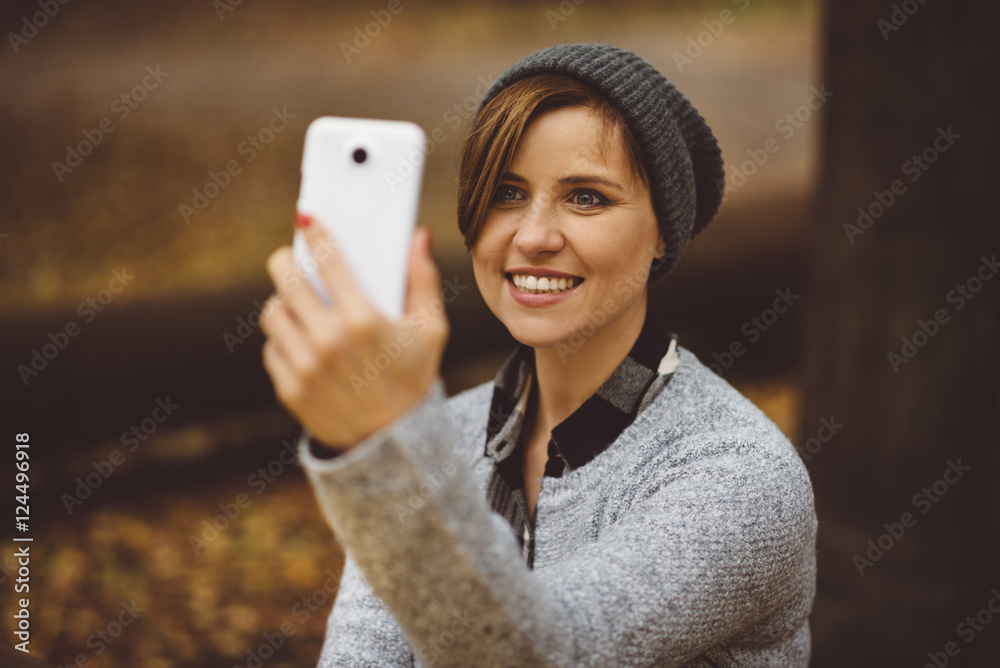 Portrait of happy, smiling woman sitting alone in the forest with smartphone. Millenial girl playing social media on the phone Portrait of happy, smiling woman sitting alone in the forest with smartphone. Millenial girl playing social media on the phone