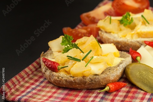 Two kinds of cheese on bread. Healthy breakfast on the kitchen table. Bread with cheese cherry tomato and chilli. 
