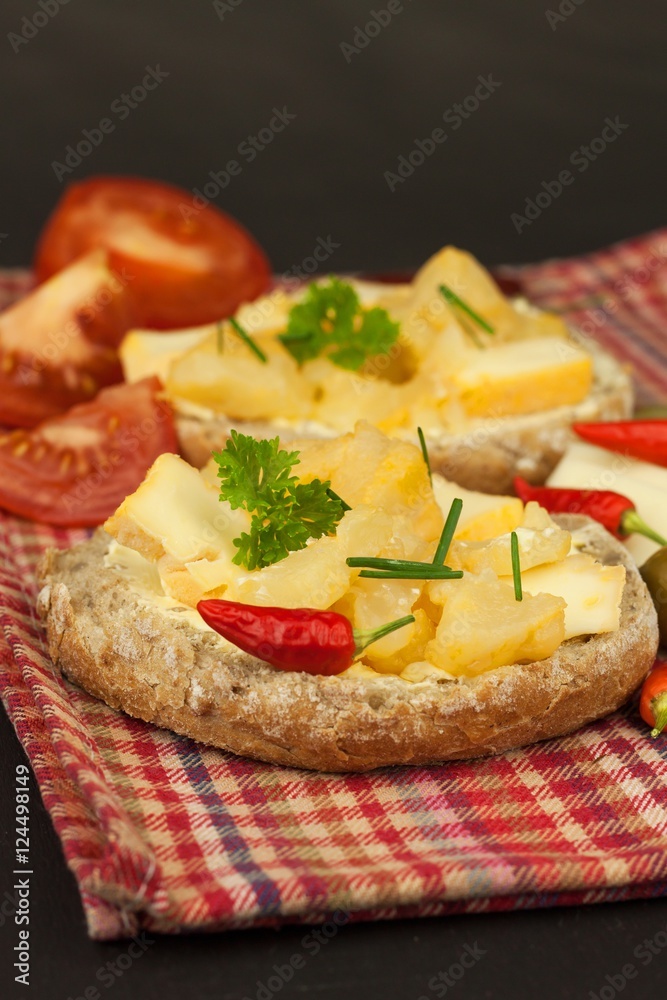 Two kinds of cheese on bread. Healthy breakfast on the kitchen table. Bread with cheese cherry tomato and chilli. 
