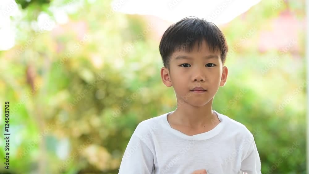Young Thai boy in white shirt drinking milk from glass in the garden Young Thai boy in white shirt drinking milk from glass in the garden