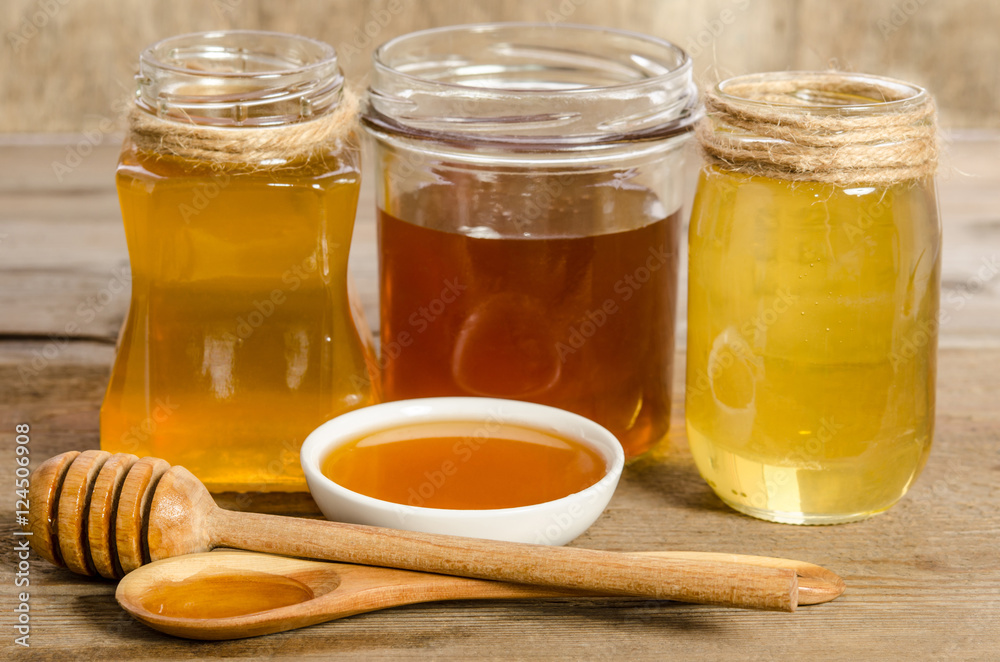 three jars,the bowl, the spoon with a honey on wooden background three jars,the bowl, the spoon with a honey on wooden background