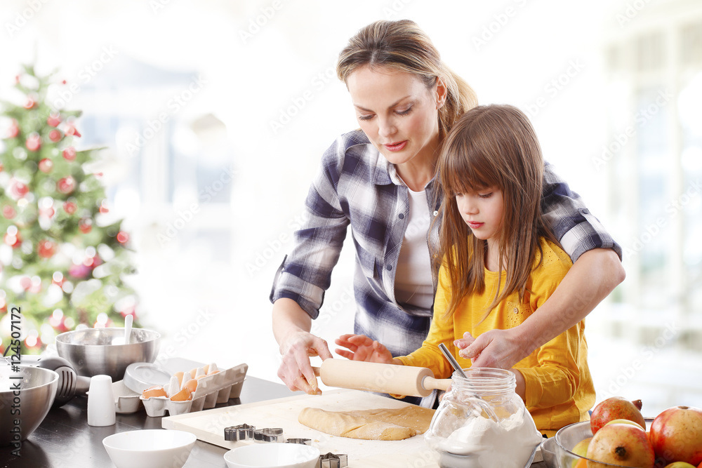 Christmas time. Portrait of cute daughter and her mom baking christmas cookies together in the kitchen. Christmas time. Portrait of cute daughter and her mom baking christmas cookies together in the kitchen.