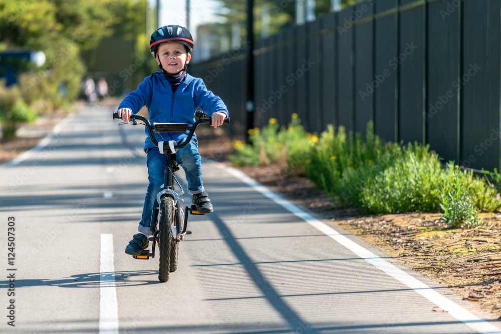 Naklejka premium Happy boy riding his bicycle on bike lane