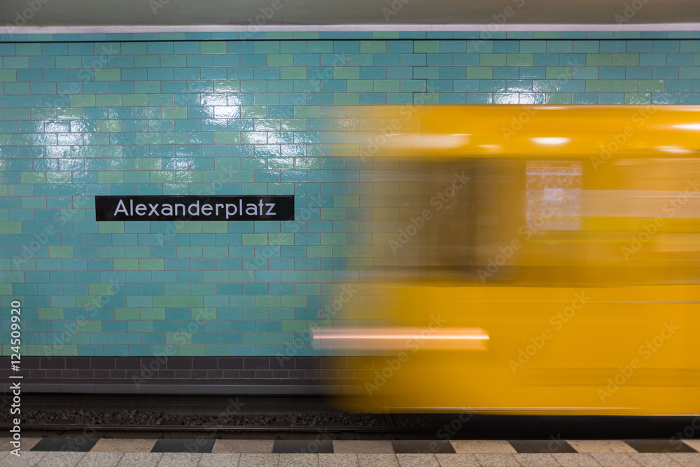 Wunschmotiv: Yellow subway train in Motion. Berlin Alexanderplatz sign visible on the wall of underg
