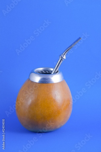yerba mate in gourd matero with bombilla on blue background