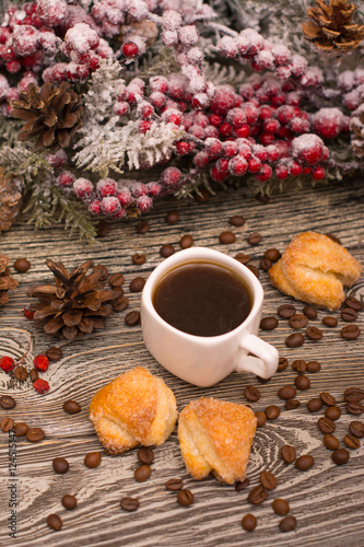 Cup of coffee, cookies, beans, fir branch in snow on wooden background
