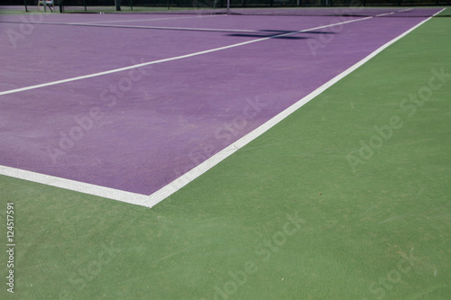 Lines of the corners of a cement tennis court. Track colors are purple and green. 
