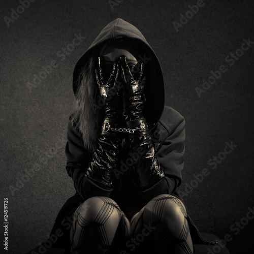 Valokuva Portrait of young woman dressed in hooded cloak, holding hands in frontof face