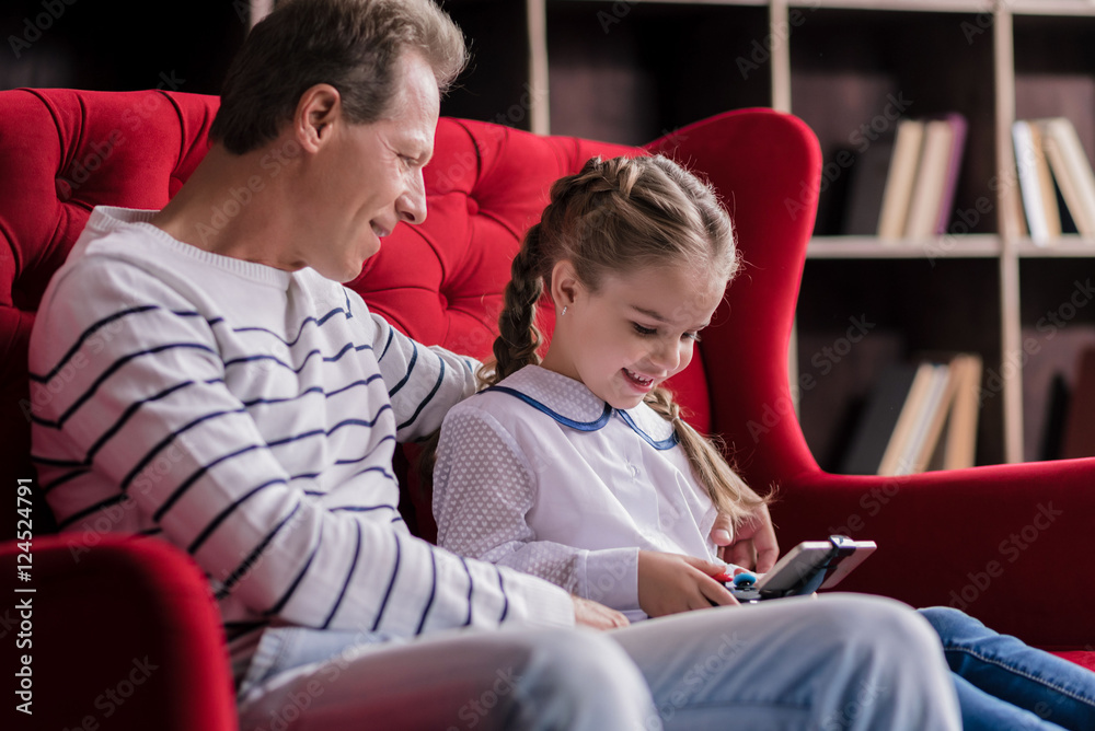 Girl resting with her grandfather and holding the game console