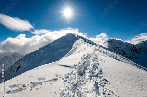 mountain tops in winter covered in snow with bright sun and blue
