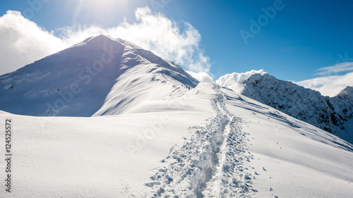 mountain tops in winter covered in snow with bright sun and blue