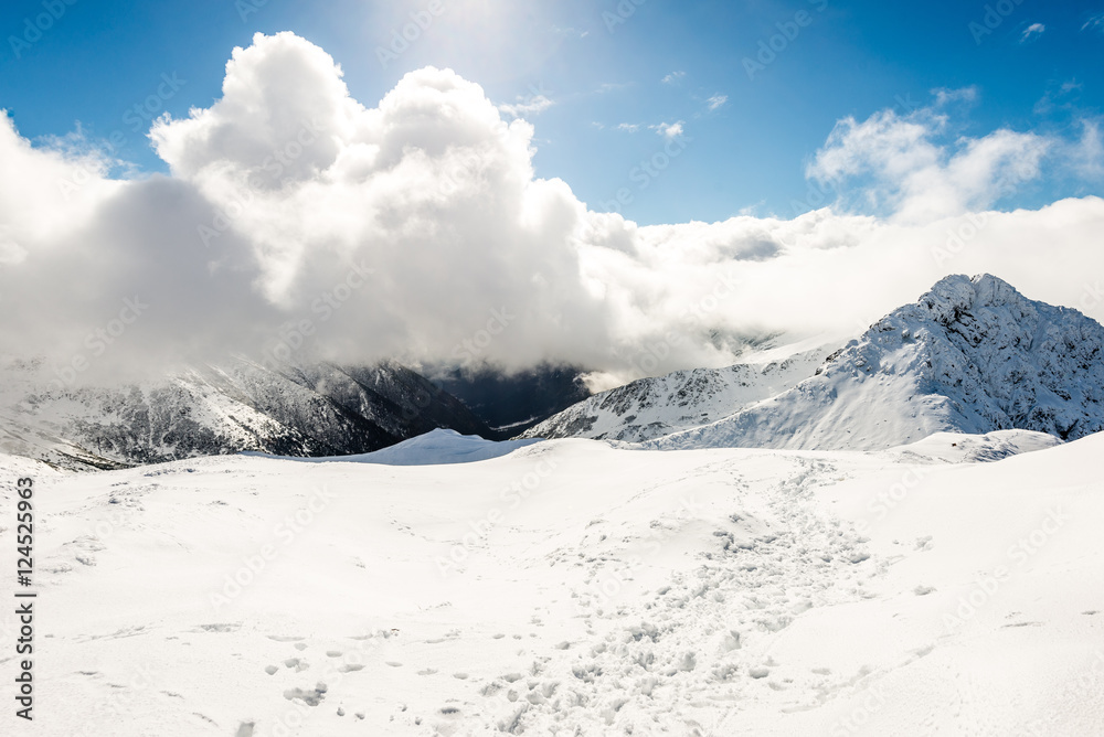 Obraz premium mountain tops in winter covered in snow with bright sun and blue