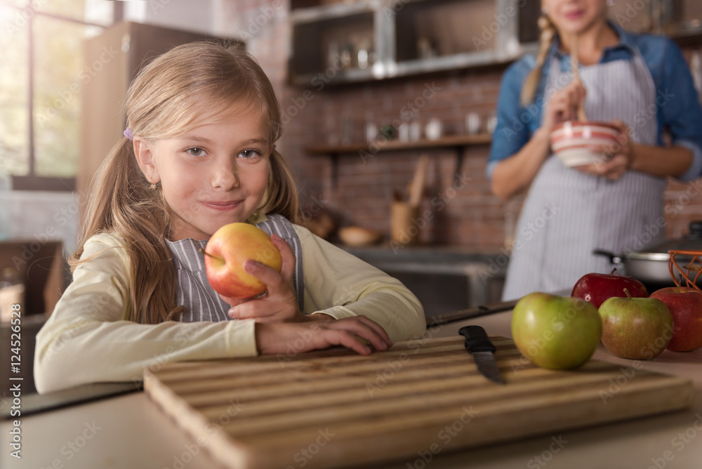 Fototapeta premium Smiling little girl holding apples in the kitchen