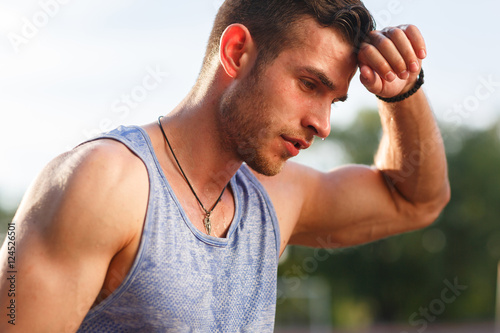Tired wet athletic man wiping sweat his hand