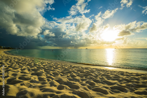 sunset on a tropical beach in the caribbean with cloudy skies and calm waters