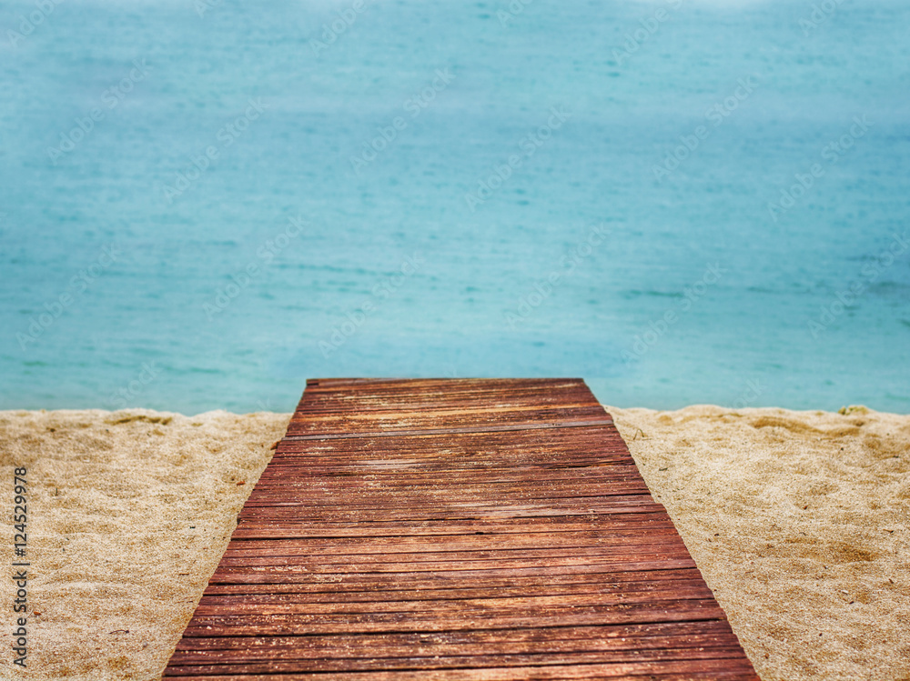 Fototapeta premium Wooden path on sand beach, sea in the background.