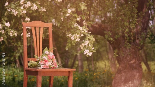 Vintage chair and flowers under blossoming apple tree