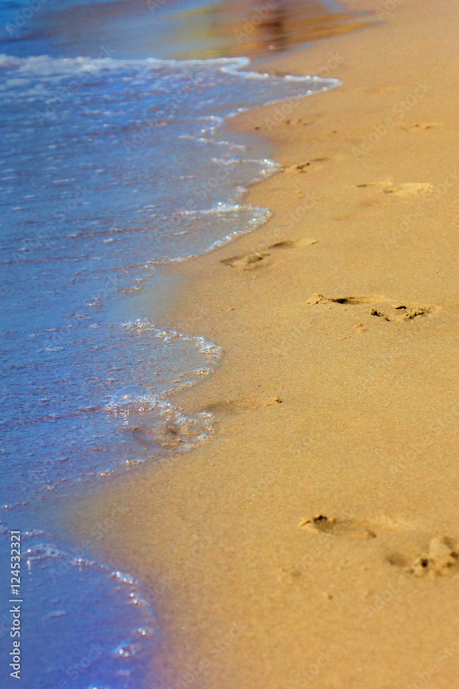 Footprints on sandy beach at sunrise