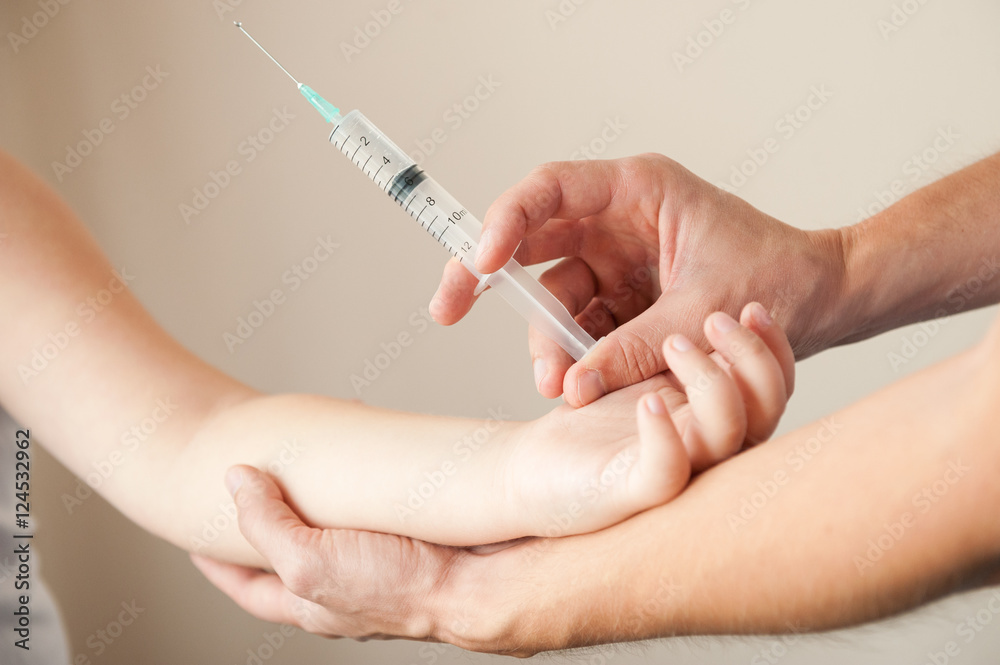 male hands with syringe holding child's hand for injection male hands with syringe holding child's hand for injection