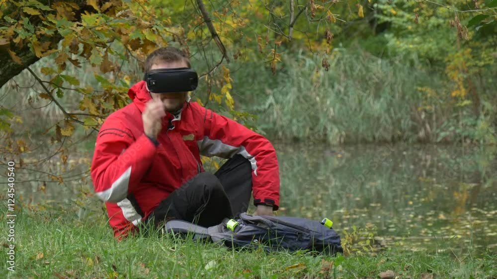 Man in vr Glasses Flinched Touched Leg Watching Video 360 Degrees Playing Virtual Games Removes the Headset Sitting on a Ground in Park by the Water