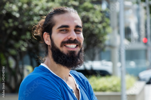 Canvas Print Laughing hipster man with beard and blue shirt in the city