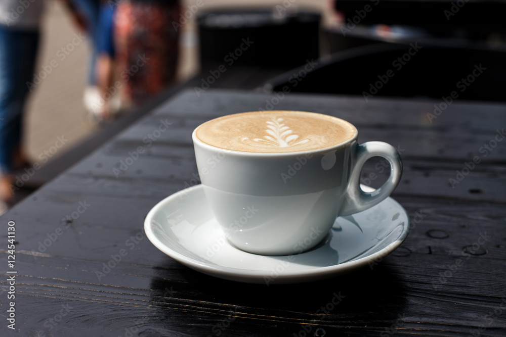 A white cup of cappuccino on the dark wooden table A white cup of cappuccino on the dark wooden table