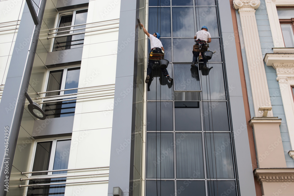 Fototapeta premium Two Workers cleaning windows service on high rise building