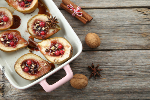 Baked pears with honey, walnuts and cranberries on grey wooden t