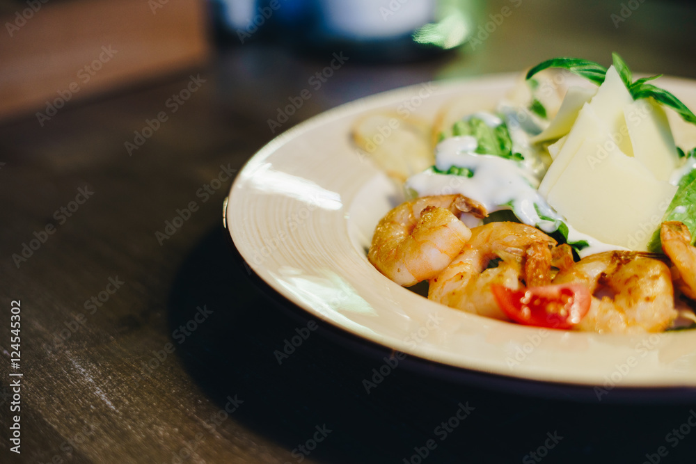 Fresh caesar salad in a circular plate on a wooden table on a blurred background Fresh caesar salad in a circular plate on a wooden table on a blurred background