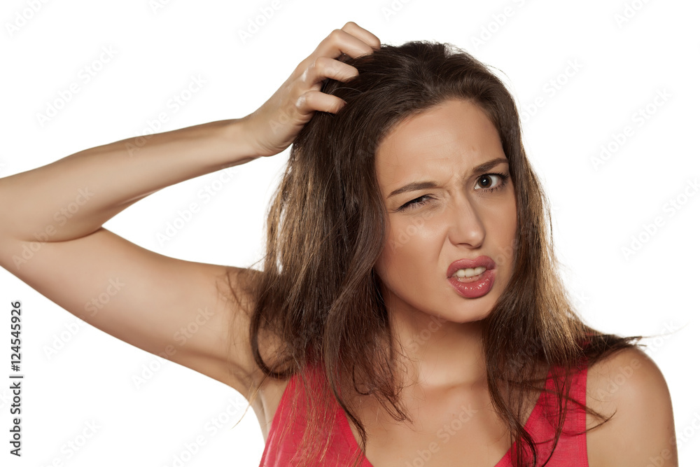 portrait of nervous young woman with itching in her hair