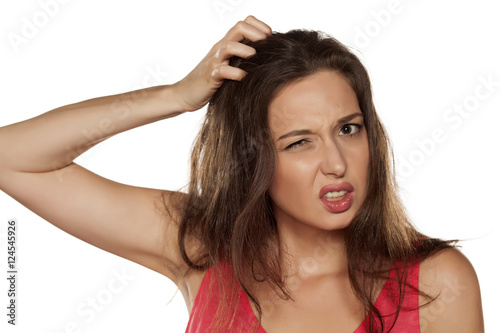 portrait of nervous young woman with itching in her hair