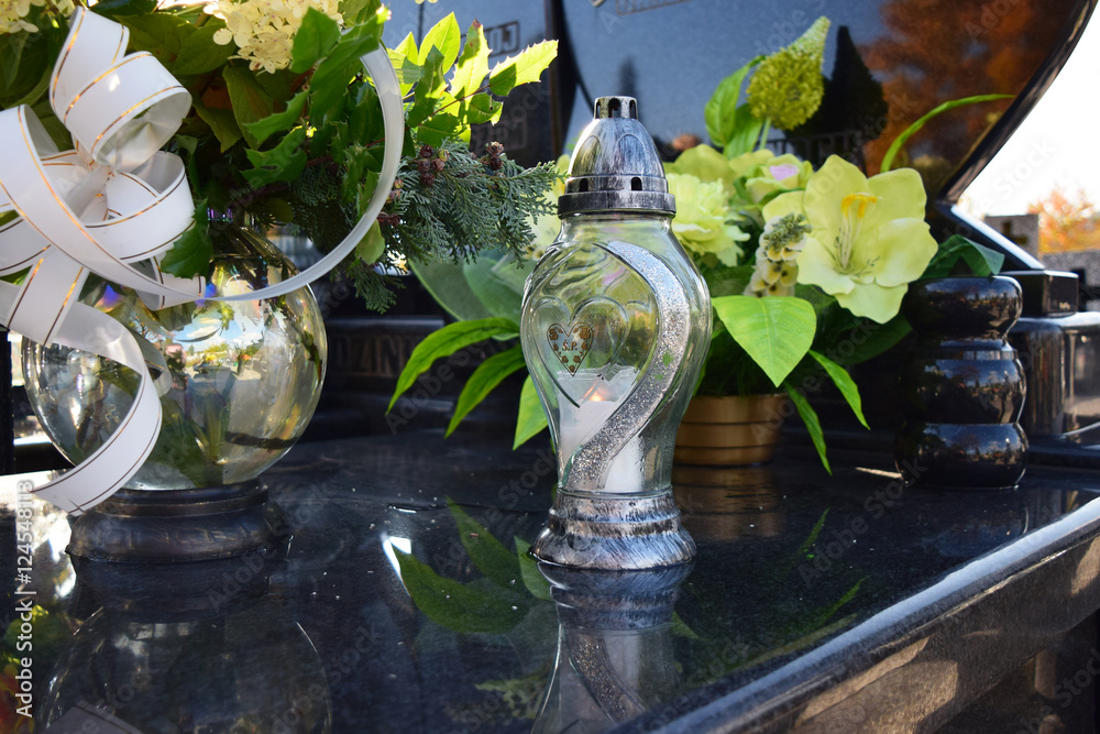 Obraz premium Zapalony znicz na grobie w dniu