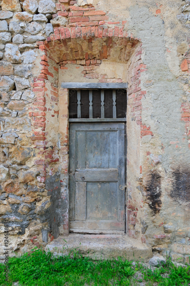 Old wooden door in brick doorway in Tuscan village.