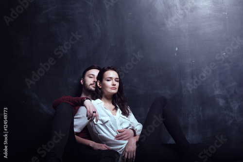 Beautiful cute loving couple in a studio with dark walls © imynzul