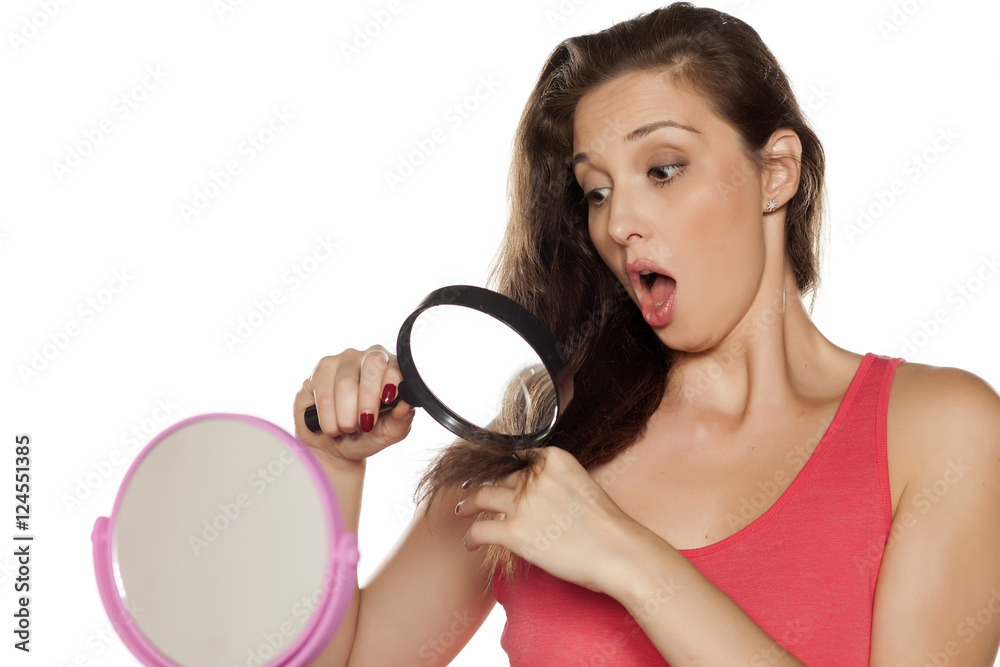 nervous young woman looking through a magnifying glass split ends of her hair nervous young woman looking through a magnifying glass split ends of her hair