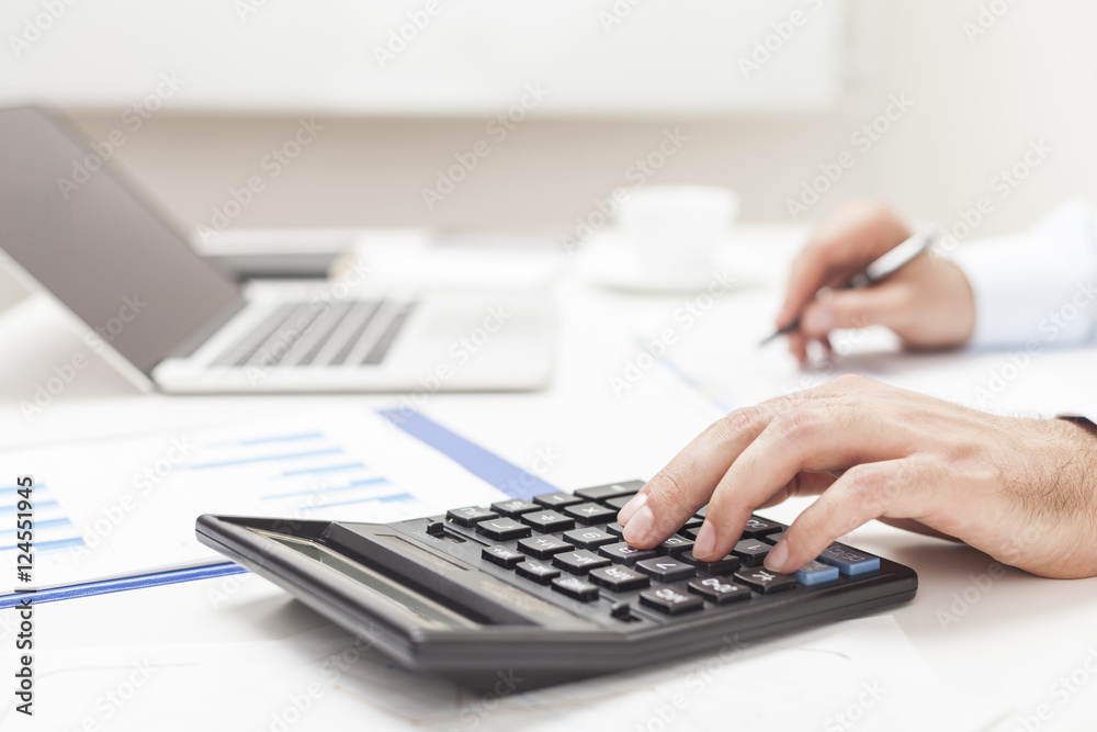 Side view of man's hands using calculator Side view of man's hands using calculator