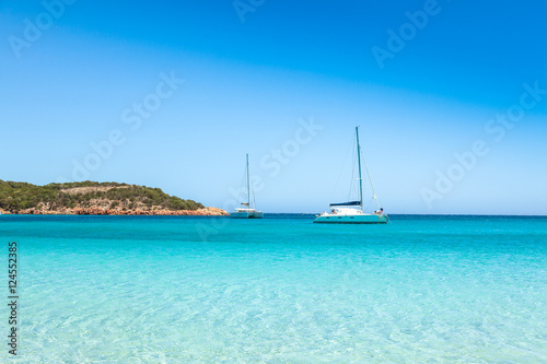 Boats mooring in the turquoise water of  Rondinara beach in Cors