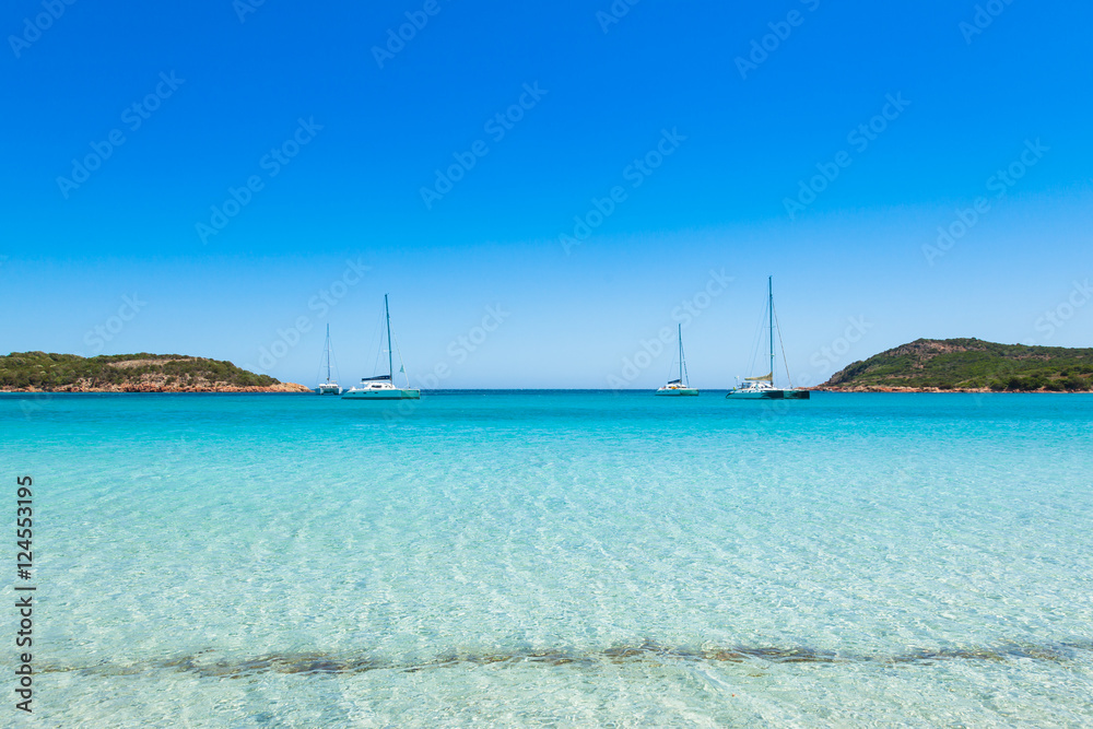 Boats mooring in the turquoise water of  Rondinara beach in Cors
