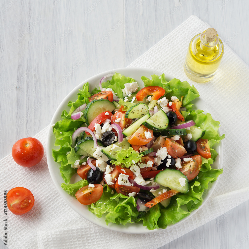 Fresh vegetable Greek salad with oil bottle, top view