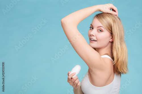Girl applying stick deodorant in armpit.