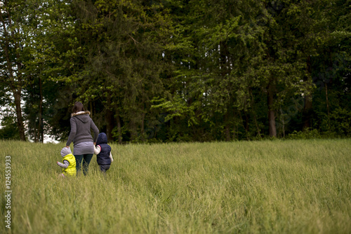 Woman walking her two children through a field