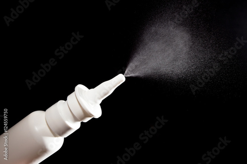Close-up of nasal drug spraying on black photo