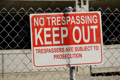 no trespassing sign on fence of construction site