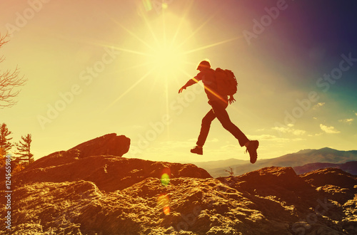Fototapet Man jumping over gap on mountain hike