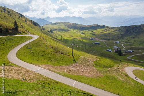 Panoramastrasse scenic road with white text on, leading up to Alpenhaus with blurred cable cars and mountains background in Kitzbuhel, Austria photo