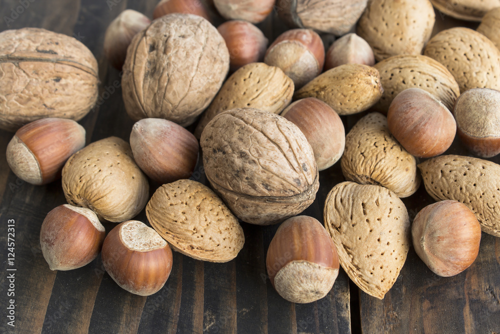 Walnuts, Hazelnuts and Almonds on a Rustic Wooden Table Walnuts, Hazelnuts and Almonds on a Rustic Wooden Table